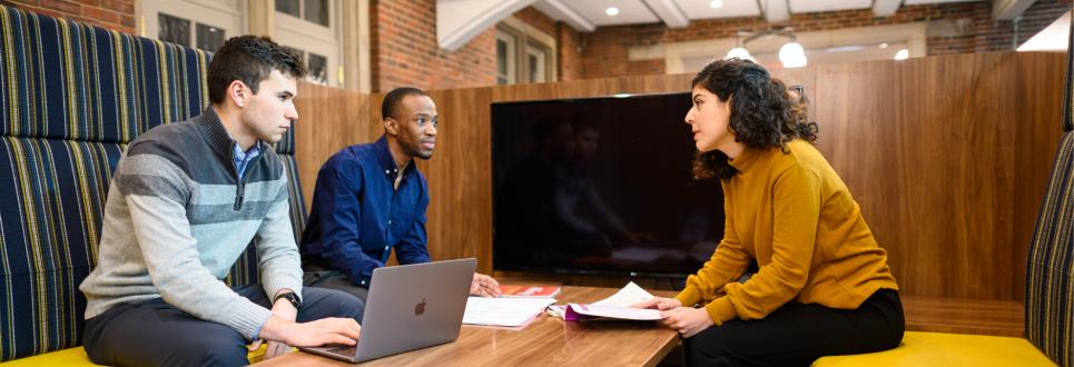 Three students having a conversation while studying