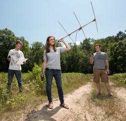 Students doing research in a field with a large antenna