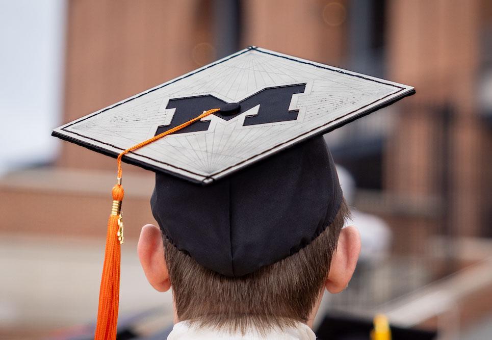 Graduate with Block-M decoration on their square graduation cap.