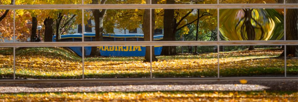 A U-M bus reflected in the glass exterior of the Power Center
