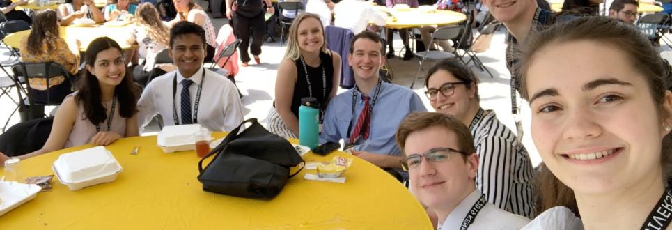 Students in business attire eating lunch at a restaurant outdoors