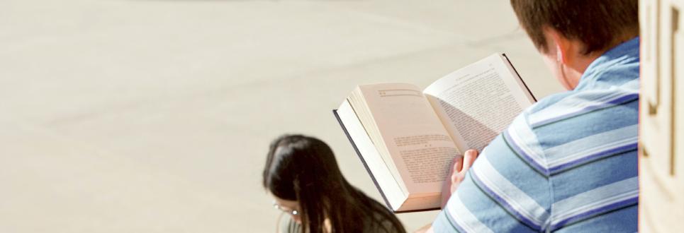 Two students reading books outdoors