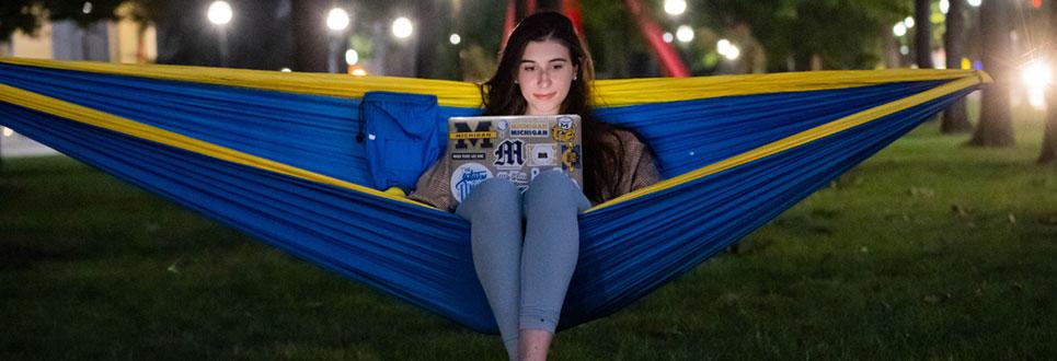 Student in hammock working on her laptop