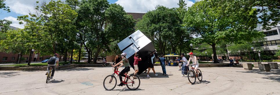 Students riding bikes around the Cube