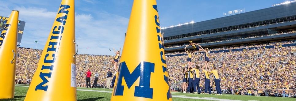 Megaphones sit on the sideline as cheerleaders perform in front of thousands of football fans at Michigan Stadium.