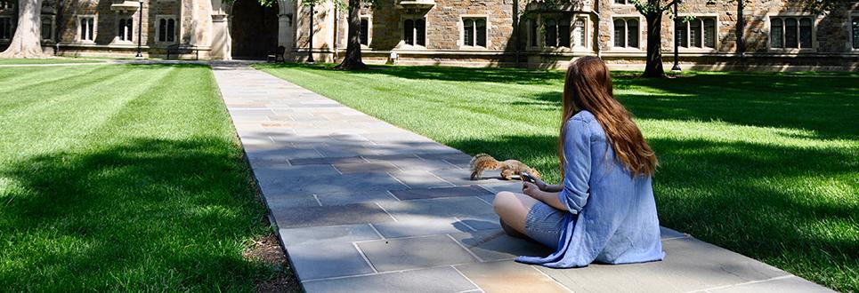 Student with a squirrel in the Law Quad
